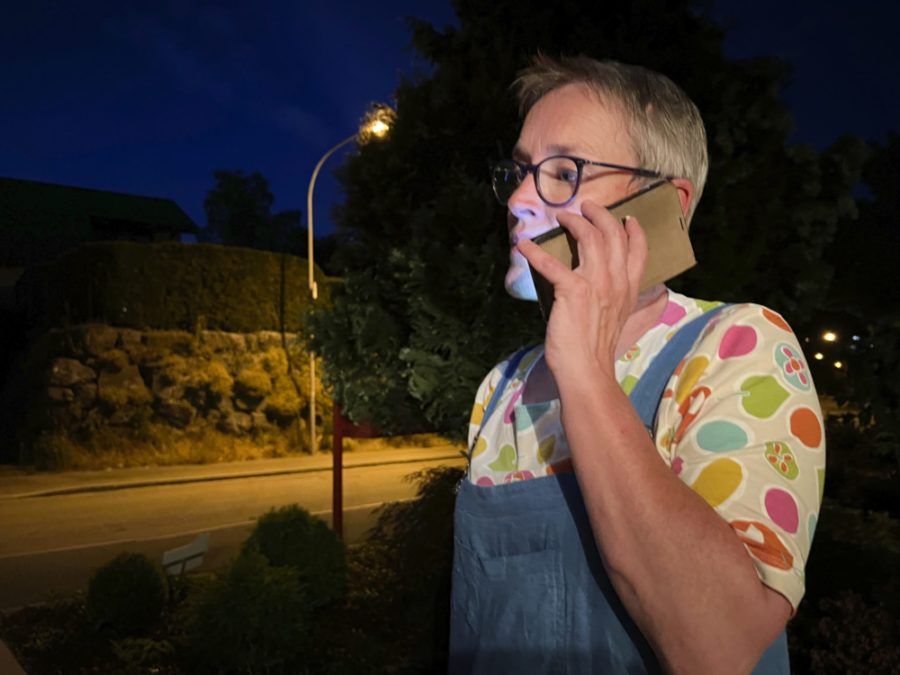 Palliaviva-Mitarbeiterin Ankie van Es steht in der Nacht auf einem Trottoir und telefoniert.