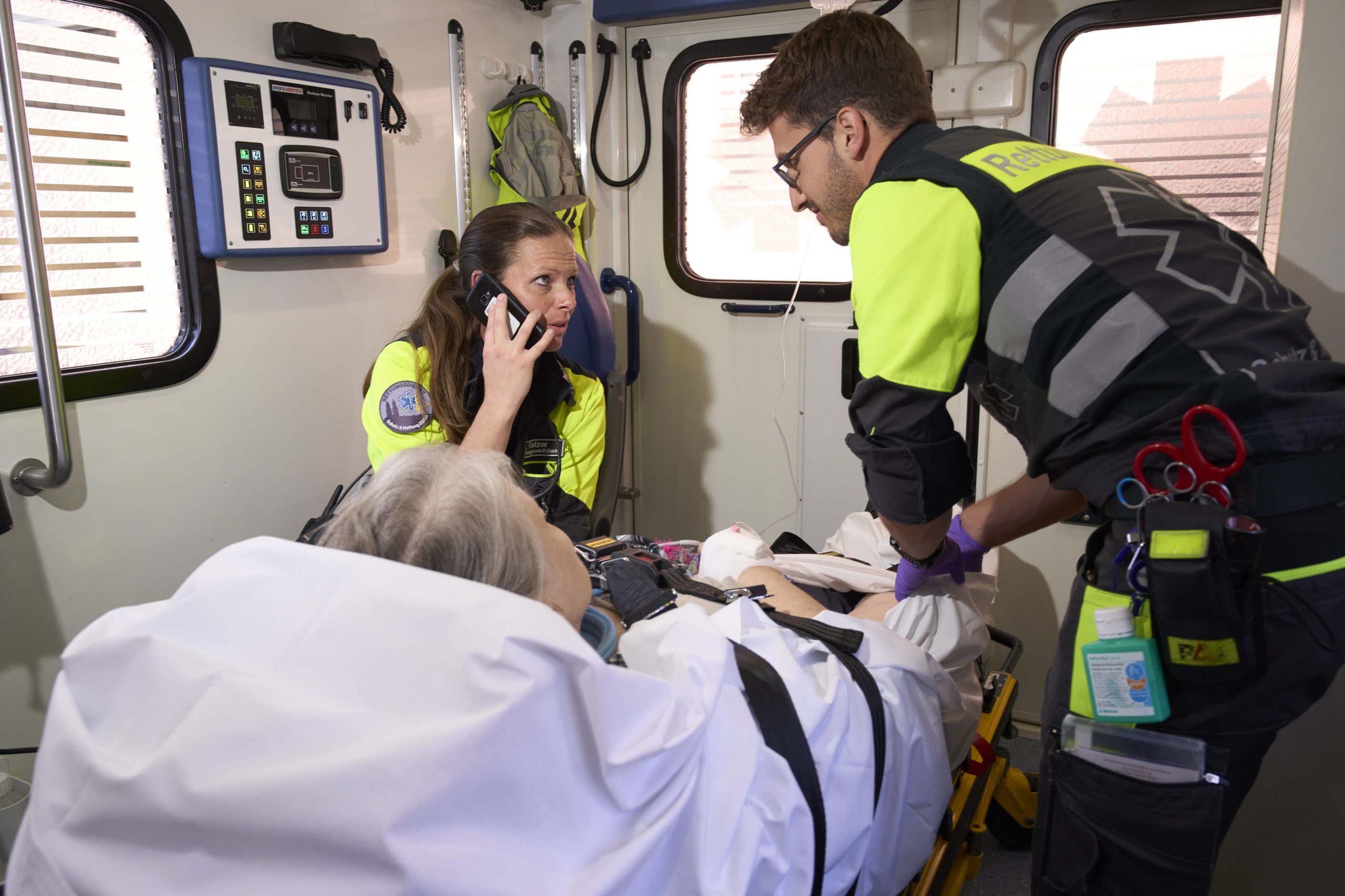 Ein Team aus zwei Rettungssanitätern betreut in einem Ambulanzfahrzeug eine Patientin.